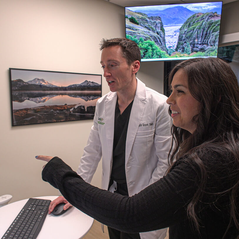 Dr. Colin Graser of Willamette Valley Periodontics speaking with a patient while looking at a computer screen.